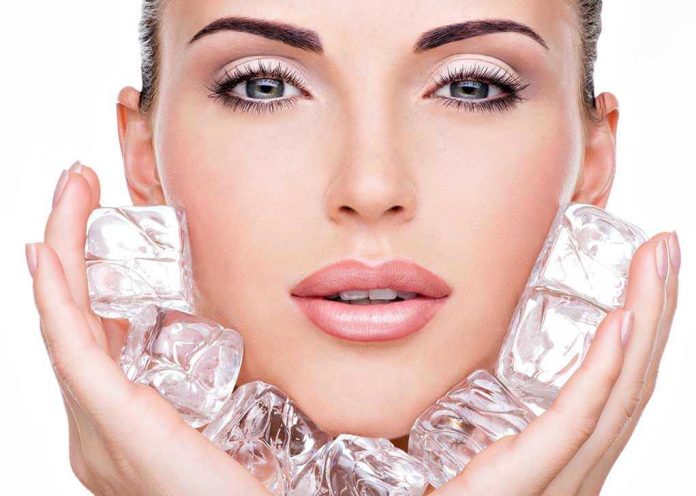 Woman holding ice cubes near her face