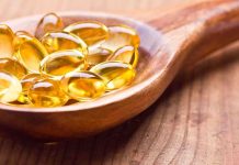 Golden omega 3 capsules in a wooden spoon