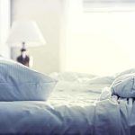 A cozy unmade bed with soft pillows and bedding in a well lit room