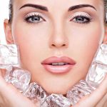 Woman holding ice cubes near her face