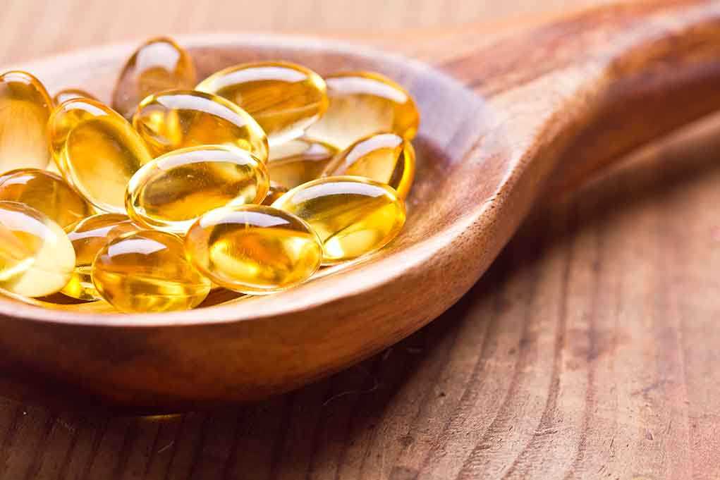 Golden omega 3 capsules in a wooden spoon