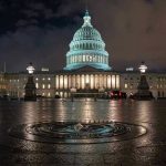 US Capitol building illuminated at night with wet pavement