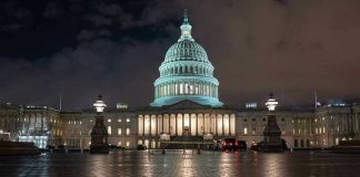 US Capitol building illuminated at night with wet pavement