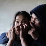 Man holding womans mouth gesturing silence