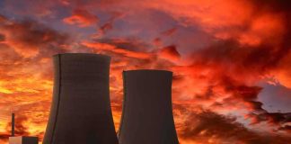 Silhouette of cooling towers against a vibrant sunset sky