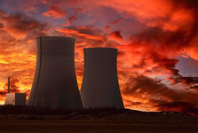 Silhouette of cooling towers against a vibrant sunset sky