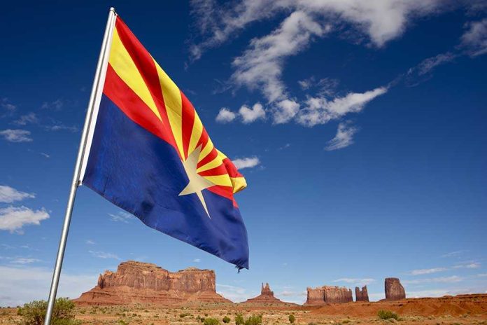 Arizona state flag waving in front of Monument Valley under a blue sky