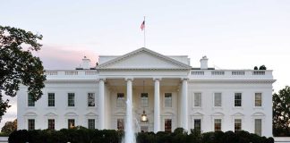 The White House with a fountain in the foreground and an American flag flying