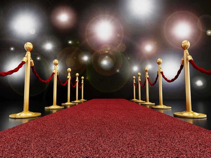 shutterstock_240259072.jpg A red carpet lined with gold stanchions and ropes under bright spotlights