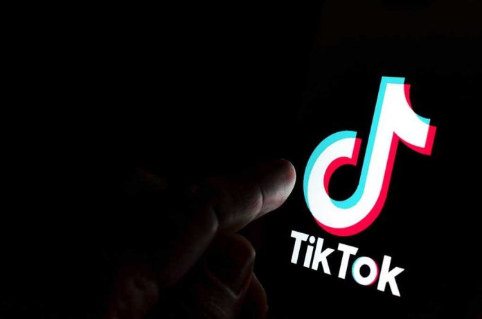 Finger pointing at TikTok logo on a screen.