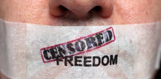 Close-up of a persons mouth covered with tape that reads CENSORED FREEDOM