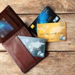 Wallet with three credit cards on wooden surface