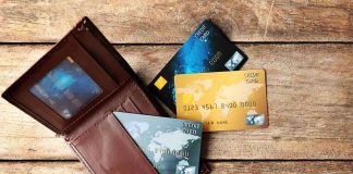 Wallet with three credit cards on wooden surface