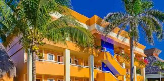 Colorful resort building surrounded by palm trees and lush greenery