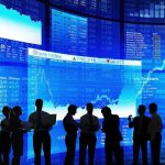 Silhouetted business professionals in front of digital stock market displays