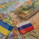 Toy tank on map with Ukraine and Russia flags.