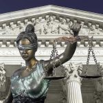 Lady Justice statue in front of courthouse.