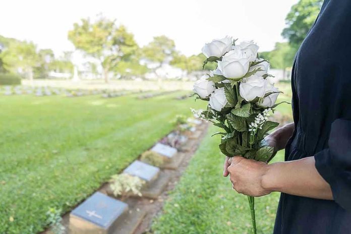 Person holding white roses at a cemetery.