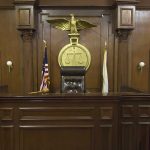 Interior of a courtroom featuring a judges bench and American flag