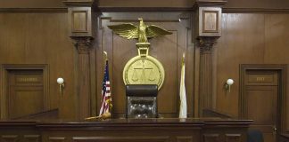 Interior of a courtroom featuring a judges bench and American flag