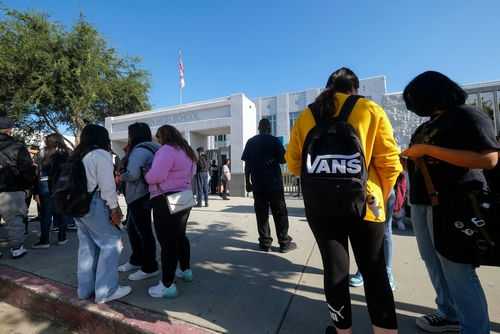 Students standing outside a high school entrance