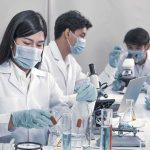 Scientists in lab coats working with test tubes and microscopes