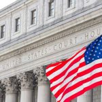 American flag waves before a neoclassical courthouse facade