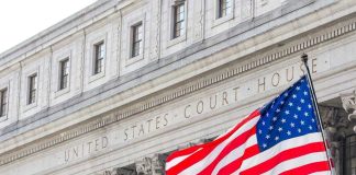 American flag waves before a neoclassical courthouse facade