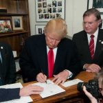 man in suit signing a document at a counter