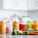 Assorted pickled vegetables in jars on a kitchen counter