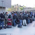 Fernando Salas and a large group of travelers waiting in a long line with luggage