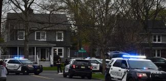 Police SUVs with lights on block a suburban street