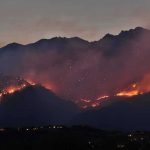 Wildfire burning along mountain slopes at dusk