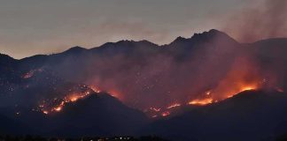 Wildfire burning along mountain slopes at dusk