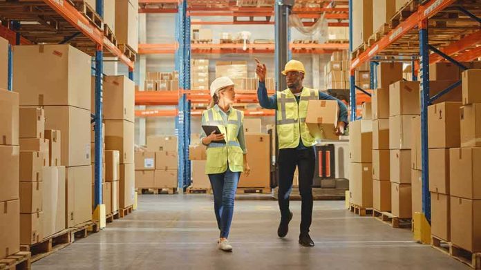 Warehouse workers walking among shelves with boxes