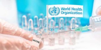 Gloved hands holding vaccine vial and syringe near WHO banner