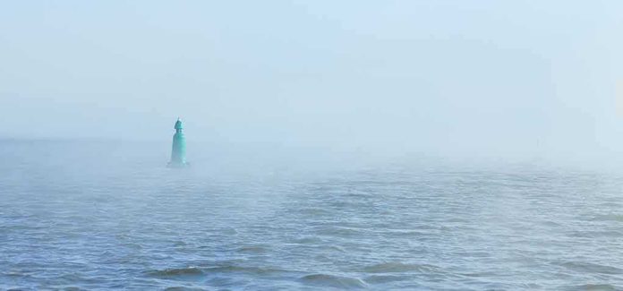 shutterstock_1870019050 Green buoy in foggy sea