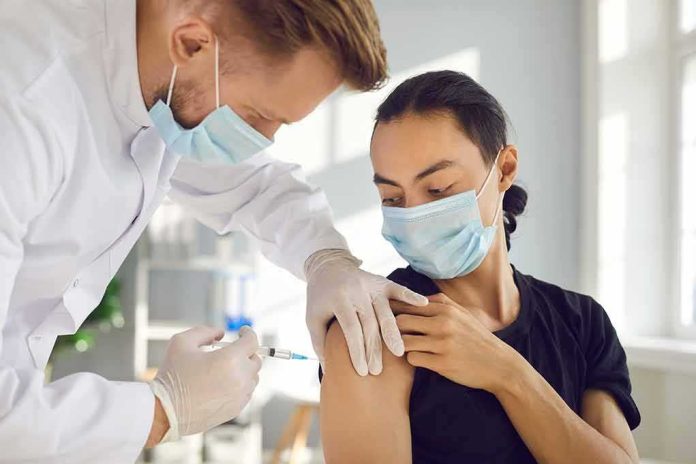 Healthcare worker giving a masked patient a vaccine in the upper arm