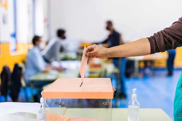 shutterstock_1967876806 Hand casting ballot into a box at a polling station