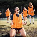 Soccer player kneeling and celebrating on field