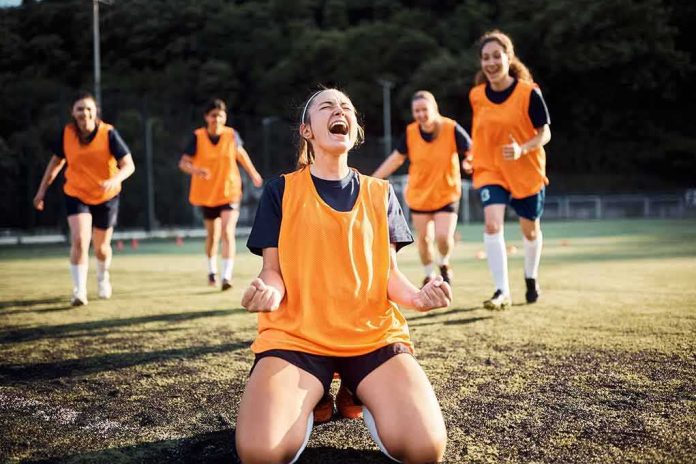 Soccer player kneeling and celebrating on field