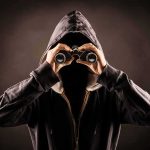 Hooded person looking through binoculars
