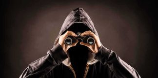 Hooded person looking through binoculars