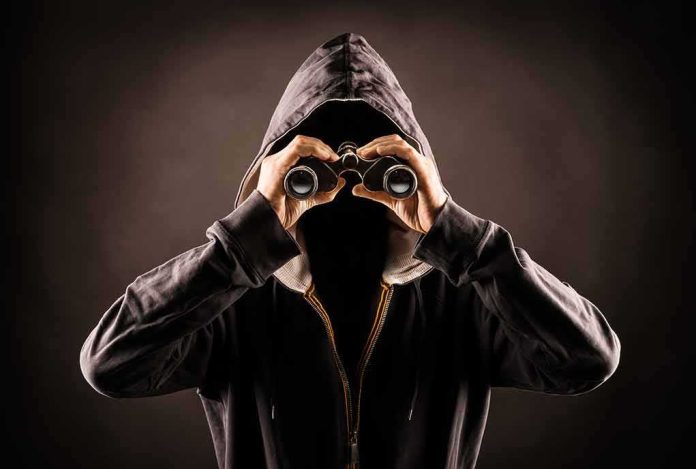 Hooded person looking through binoculars