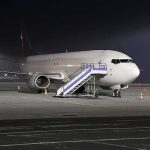 Passenger airplane parked on tarmac at night with mobile stairs