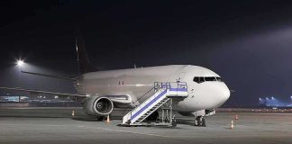 Passenger airplane parked on tarmac at night with mobile stairs