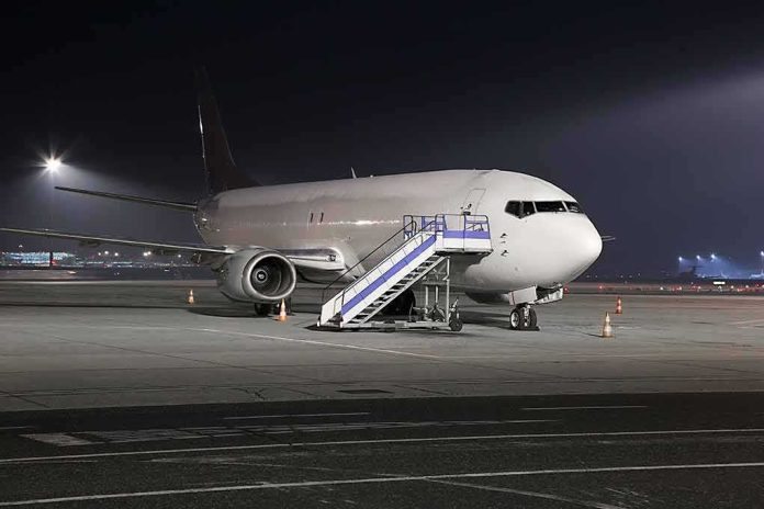 shutterstock_421245067 Passenger airplane parked on tarmac at night with mobile stairs