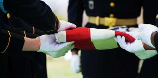 Missiles Hit—Sergeant’s Daring Turned Tides Military personnel folding a flag during a ceremonial event