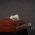 Wooden casket with white lilies and lit candles