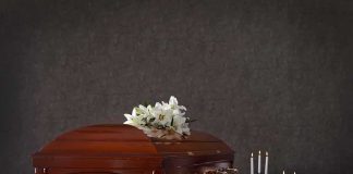 Wooden casket with white lilies and lit candles